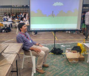 Researcher seated at the ISUS stand with a projection behind