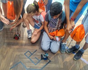 Children crouching around a robot on the floor