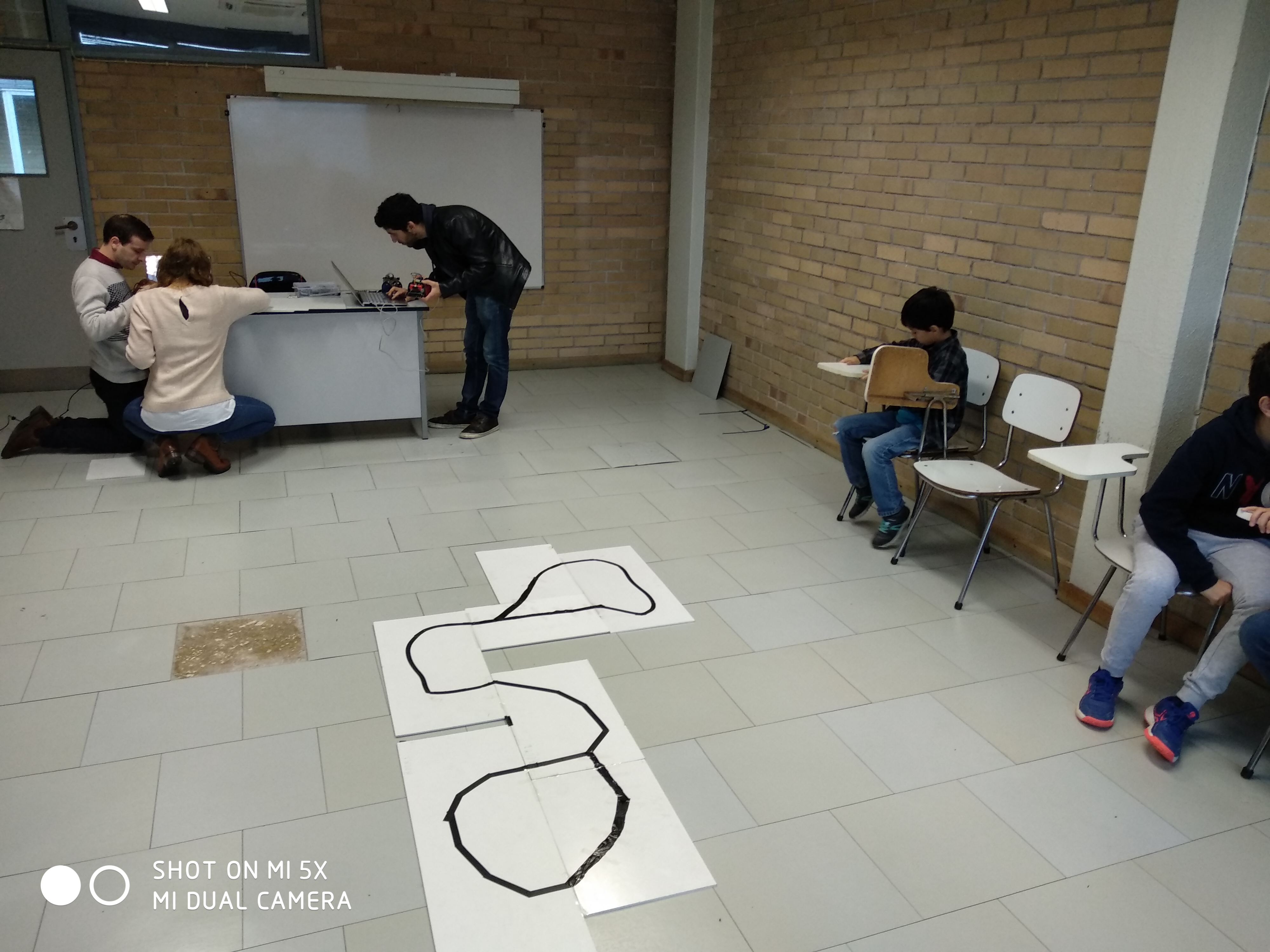 Children and researchers around the robot track in the classroom