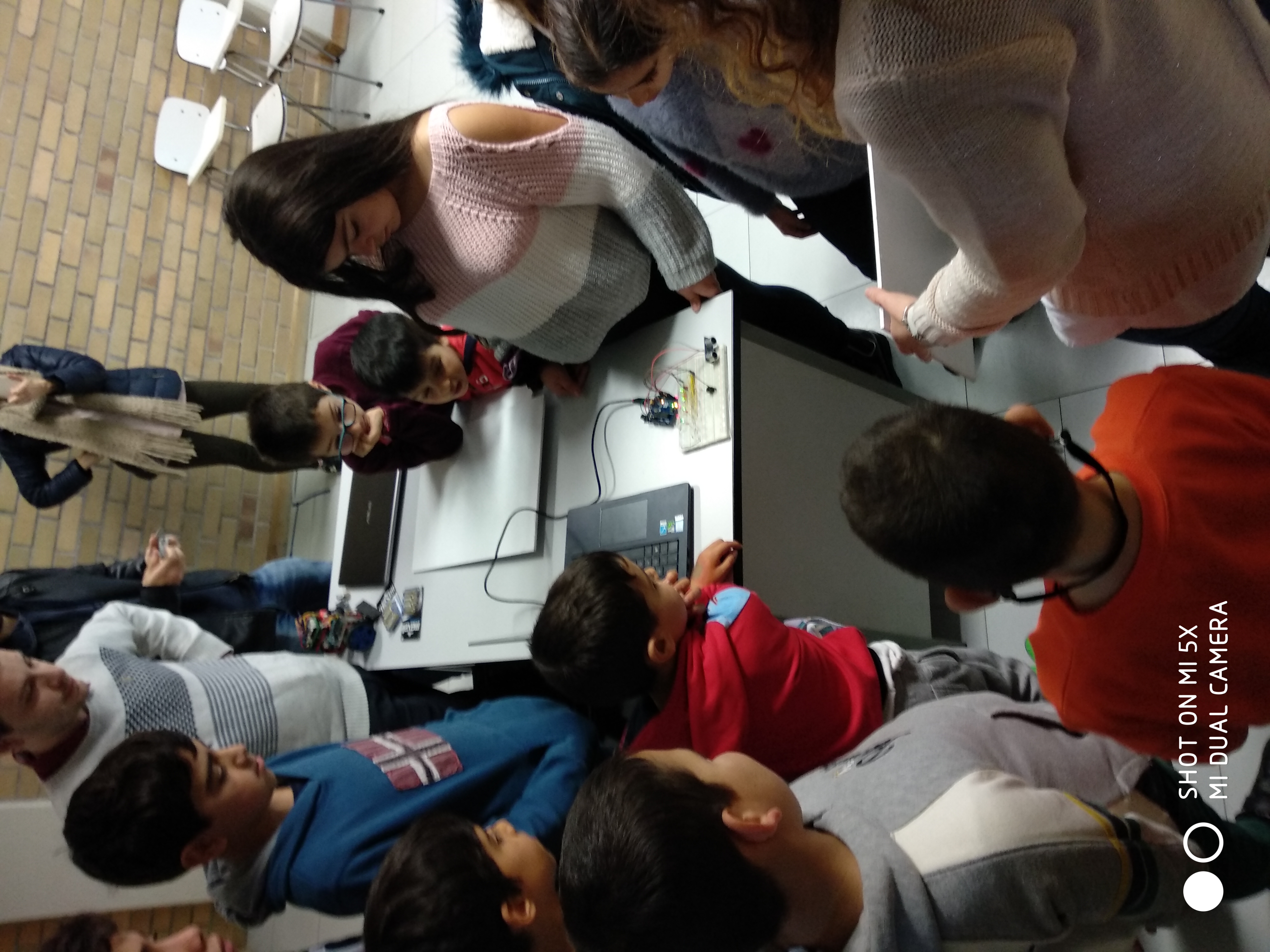 Children gathered around a desk watching a demonstration