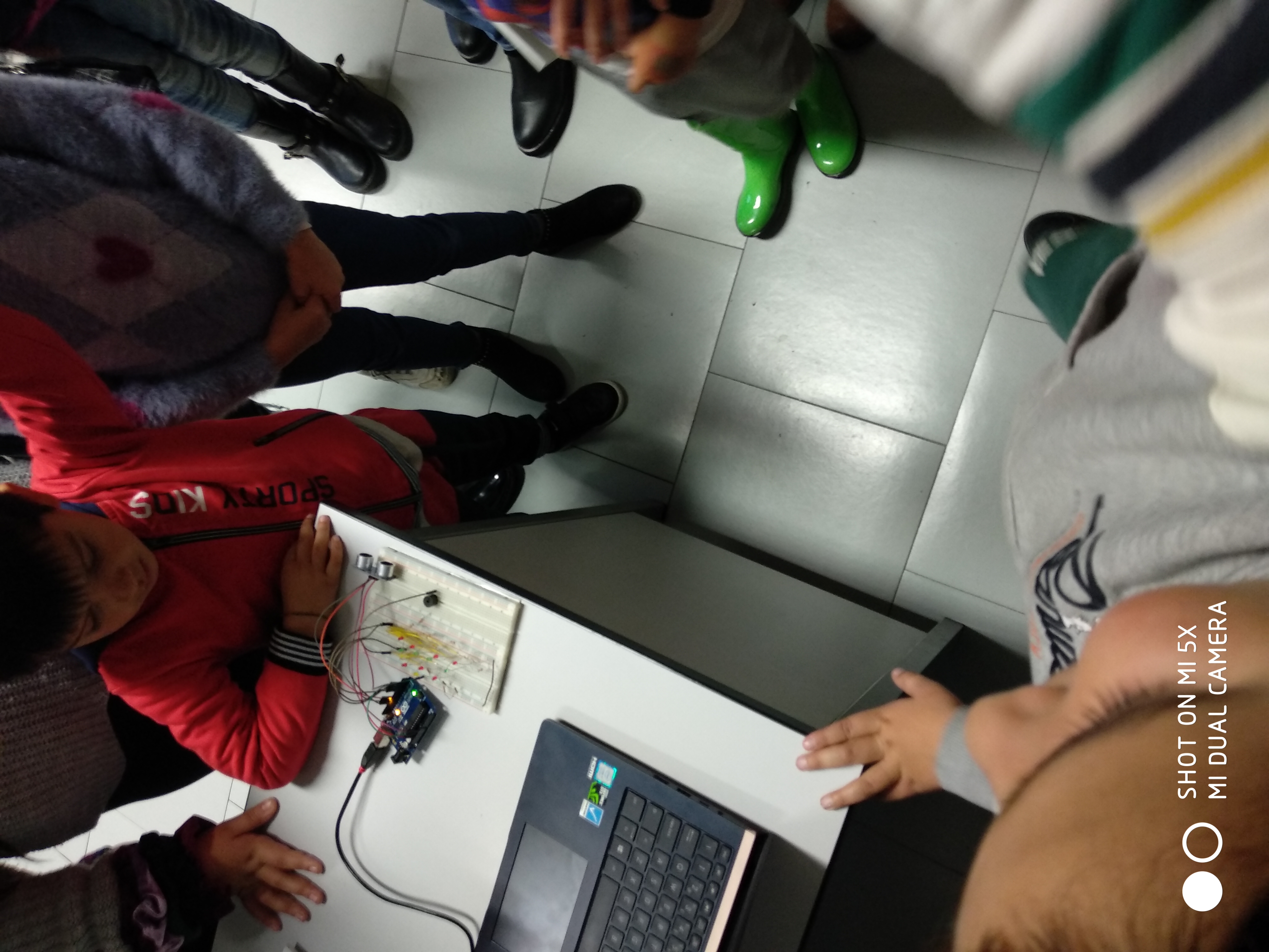 Children looking at an Arduino board connected to a laptop