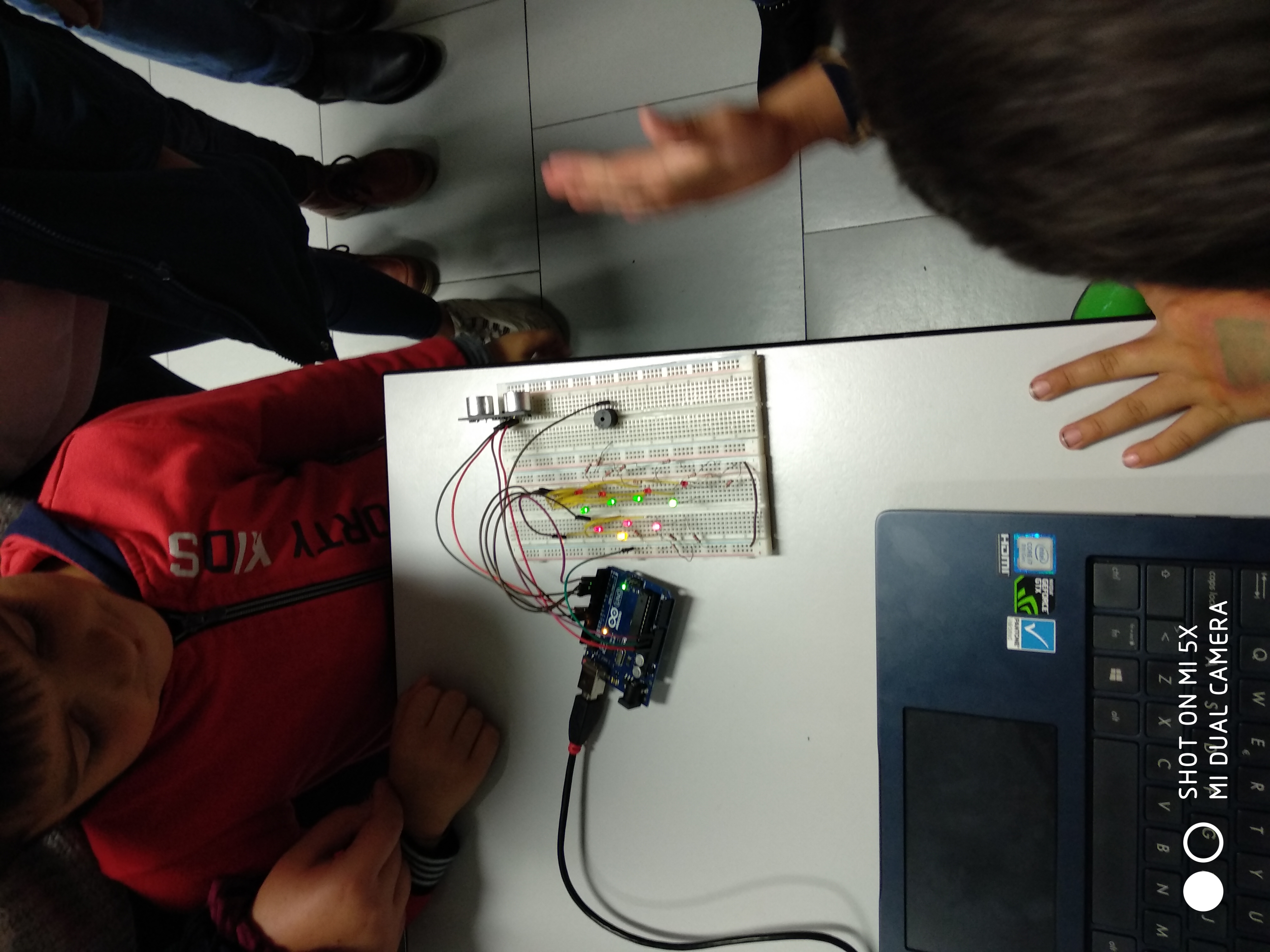 Close-up of an Arduino board and breadboard circuit next to a laptop