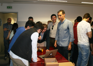 Students and teachers gathered around a table with robots