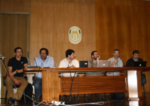 Panel of speakers seated at a table in an auditorium
